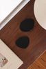 Schwarzer Designer-Lederuntersetzer mit sanft organischer Form, präsentiert auf dunklem Holz und genutzt für einen Cappuccino