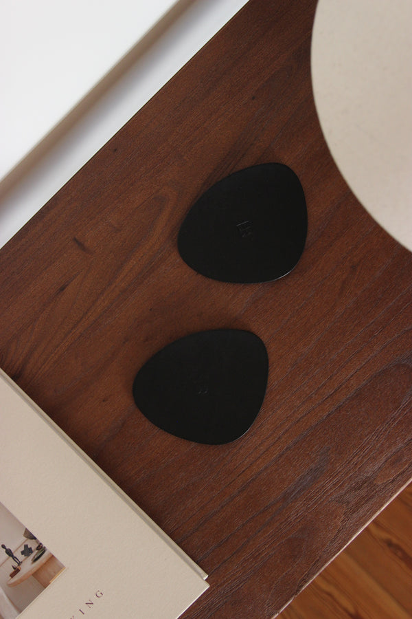 Minimalistische Glasuntersetzer aus schwarzem Naturleder in organischer Form, im eleganten Wohnzimmer mit Cappuccino-Becher