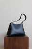 Schwarze Lederschultertasche aus pflanzlich gegerbtem Leder in seitlicher Ansicht.