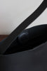 Detailansicht des innenliegenden Magnetverschlusses der schwarzen Schultertasche.
